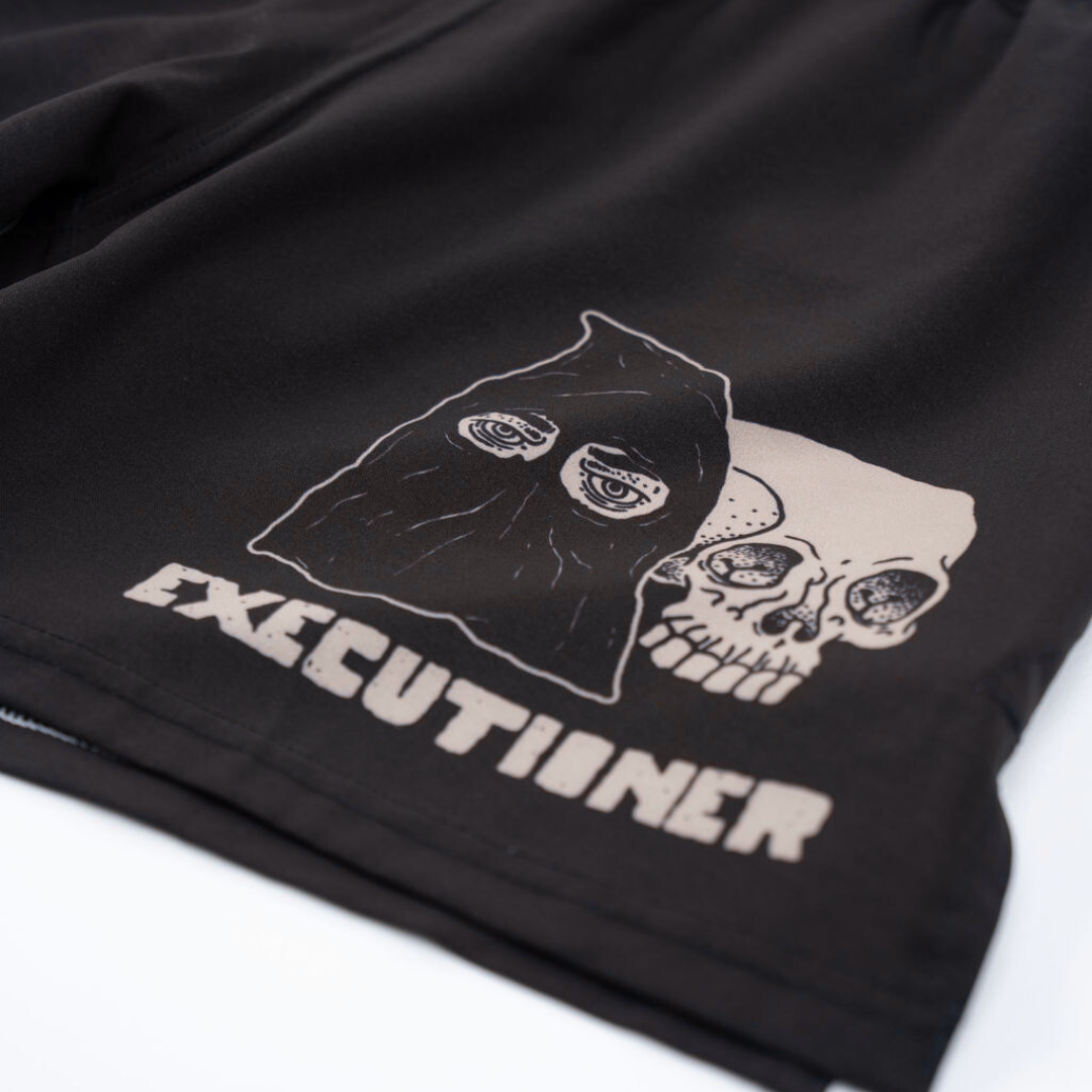 True Illusion BJJ Shorts Executioner, close-up of leg graphic showing hooded skull illustration and Executioner text print