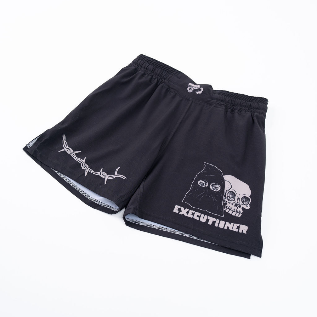 True Illusion BJJ Shorts Executioner, angled flat lay showing hooded figure and skull graphic with barbed wire side print