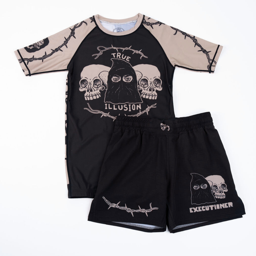 True Illusion BJJ Shorts Executioner, front flat lay styled with matching rash guard showing skull and barbed wire graphics