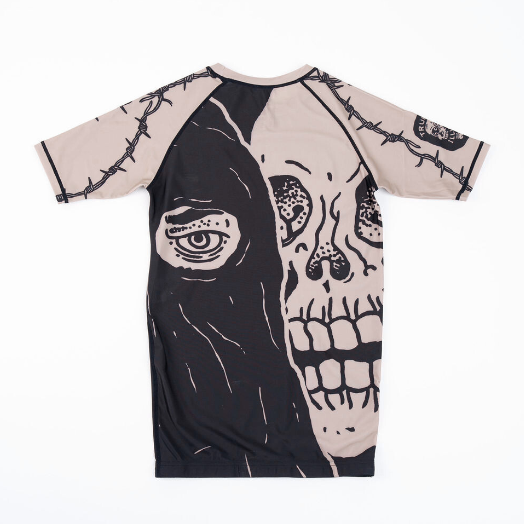 True Illusion Executioner Short Sleeve BJJ Rash Guard, back view flat lay showing hooded skull graphic and barbed wire