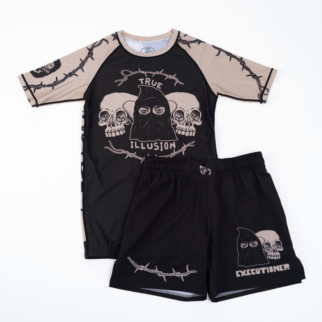 True Illusion BJJ Shorts – Executioner, front flat lay styled with matching rash guard showing skull and barbed wire graphics